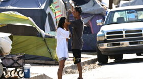 Roni and John pour water on themselves to cool off from extreme heat while residing in "The Zone," a vast homeless encampment where hundreds of people reside, during a record heat wave in Phoenix, Arizona. (Photo by PATRICK T. FALLON/AFP via Getty Images)