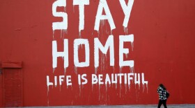 A pedestrian walks past a mural which reads "Stay at Home, Life is Beautiful" Thursday, April 2, 2020, in Los Angeles. (Marcio Jose Sanchez/AP Photo)