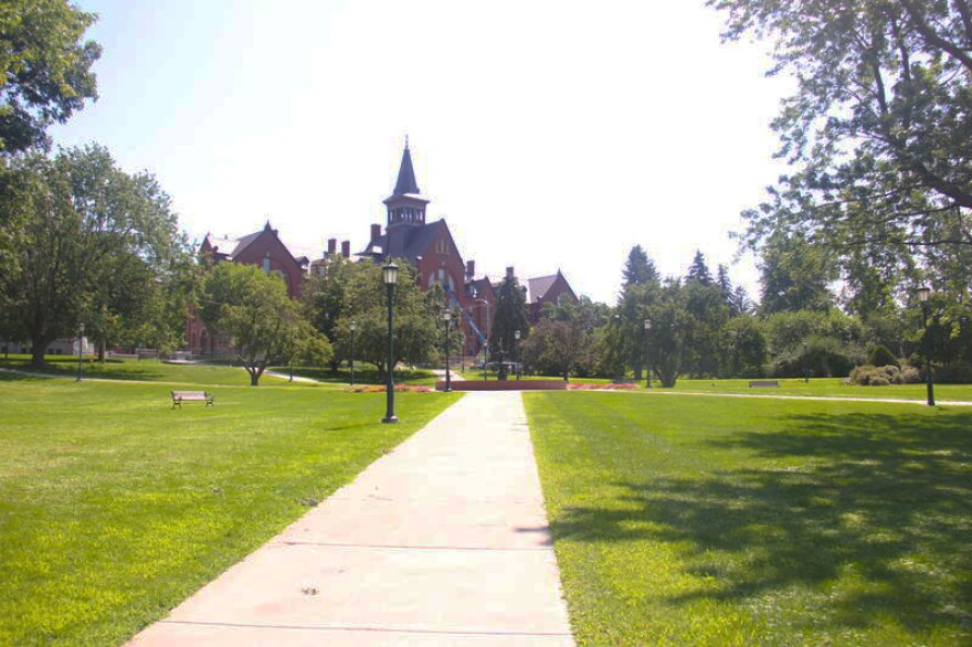 A sidewalk leading into a green grassy area with a building in the background