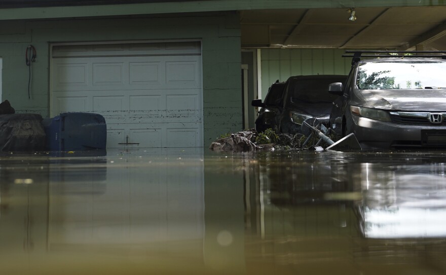 Vehicles sit in water in front of a flooded home in Indianapolis, Sunday, Aug. 16, 2026.