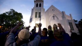 FILE - The men of Omega Psi Phi Fraternity Inc., lead a crowd of people in prayer outside the Emanuel AME Church on June 19, 2015, after a memorial in Charleston, S.C. Thousands gathered at the College of Charleston TD Arena to bring the community together after nine people where shot to death at the church days prior. After mass shootings, the loss felt by marginalized groups already facing discrimination is compounded. Some public health experts say the risk for post-traumatic stress disorder is greater for the groups, especially when the shootings take place at schools, churches and other vital hubs. (AP Photo/Stephen B. Morton, File)