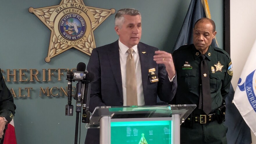 Florida Department of Law Enforcement Commissioner Mark Glass is at the media event along with (on the right) Leon County Sheriff Walt McNeil.