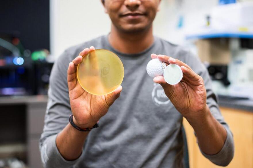 Ram Gupta holds up a sample of a polymer made from soybean oil, and an early prototype golf ball.