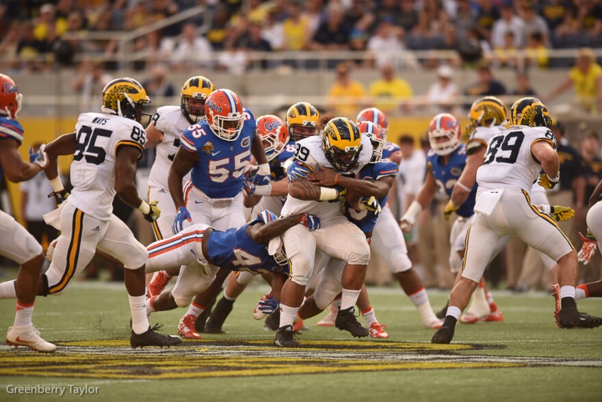 A swarm of Florida defenders try and bring down Michigan full back Sione Houma (39) in the second half. (Greenberry Taylor/WUFT News)