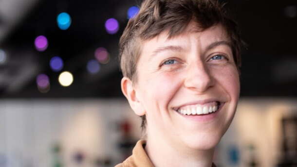 Person in a brown shirt smiling in an indoor space