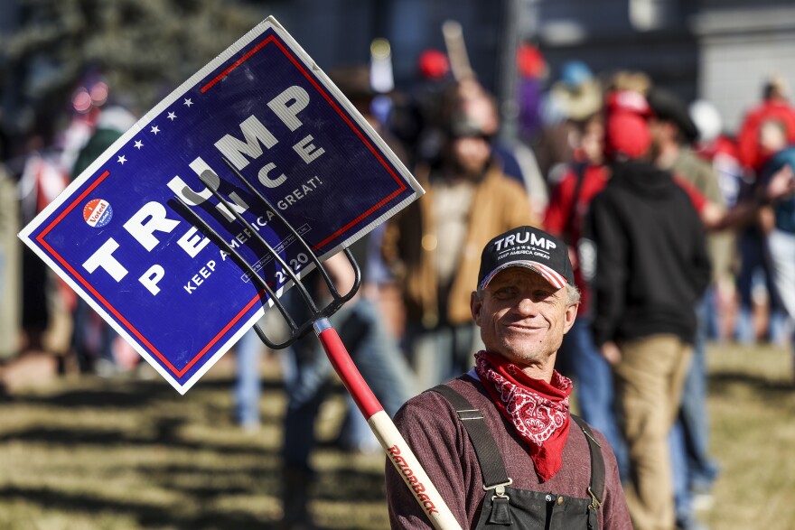A Trump supporter holds a sign with a pitchfork as he protests the election outside the Colorado State Capitol on Jan. 6 in Denver.