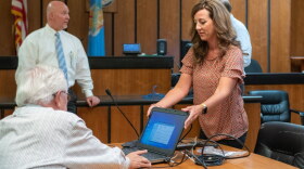McCurtain County Assistant District Attorney Emily Maxwell Herron, right, sets up a computer in a courtroom so a doctor can provide expert testimony by video.