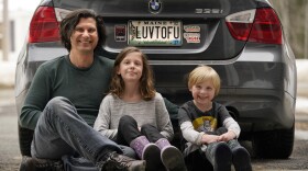 Peter Starostecki and his kids Sadie, center, and Jo Jo, pose behind their car with the vanity license plate that the state of Maine has deemed in appropriate, Wednesday, March 8, 2023, in Poland, Maine. The vegan family's car will soon have a randomly selected plate.