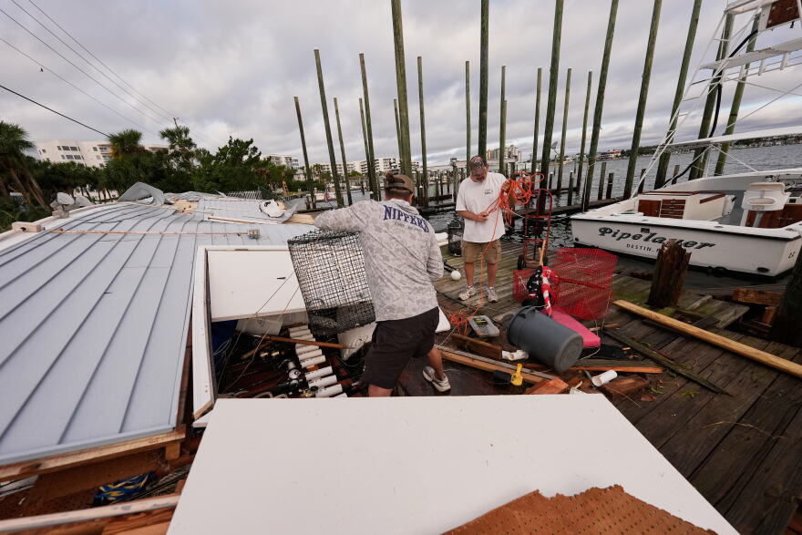 People retrieve belongings from a collapsed boat house in the aftermath of Hurricane Isaias in Destin, Fla., Saturday, Oct. 10, 2026. (AP Photo/Gerald Herbert)