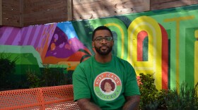 A man in a green and orange shirt sits on an orange bench.