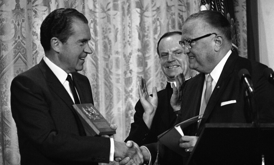 In 1969, FBI Director J. Edgar Hoover presents a gold badge to President Richard Nixon, making him an honorary member of the agency, during graduation ceremonies for the FBI National Academy.