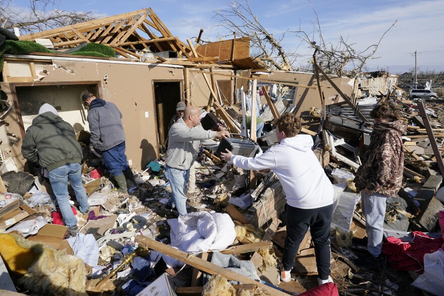 People help retrieve items from a destroyed home Saturday, Dec. 11, 2021, in Mayfield, Ky.