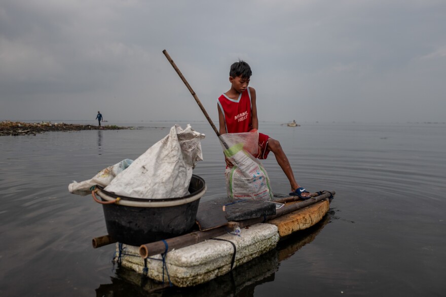 Children fill sacks with plastic trash from Manila Bay that they intend to sell to recyclers.