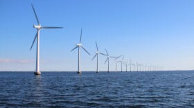 Perspective line of ocean wind mills with dark water and sky