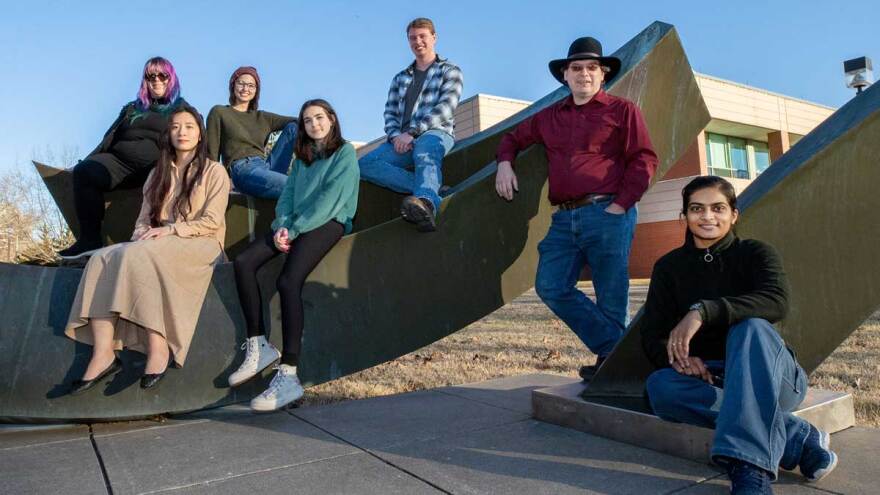 Group poses on sculpture