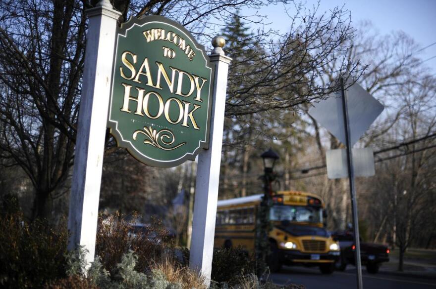 A bus drives past a sign reading Welcome to Sandy Hook in Newtown, Connecticut.