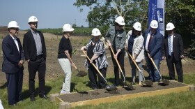 Eight people lined up at ceremonial groundbreaking
