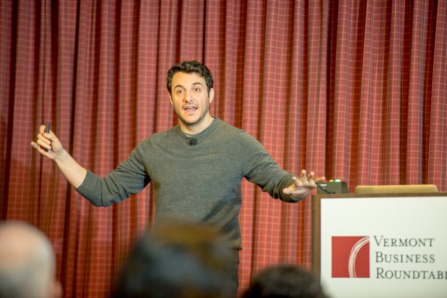 Tim Urban stretches out his arms on stage. 