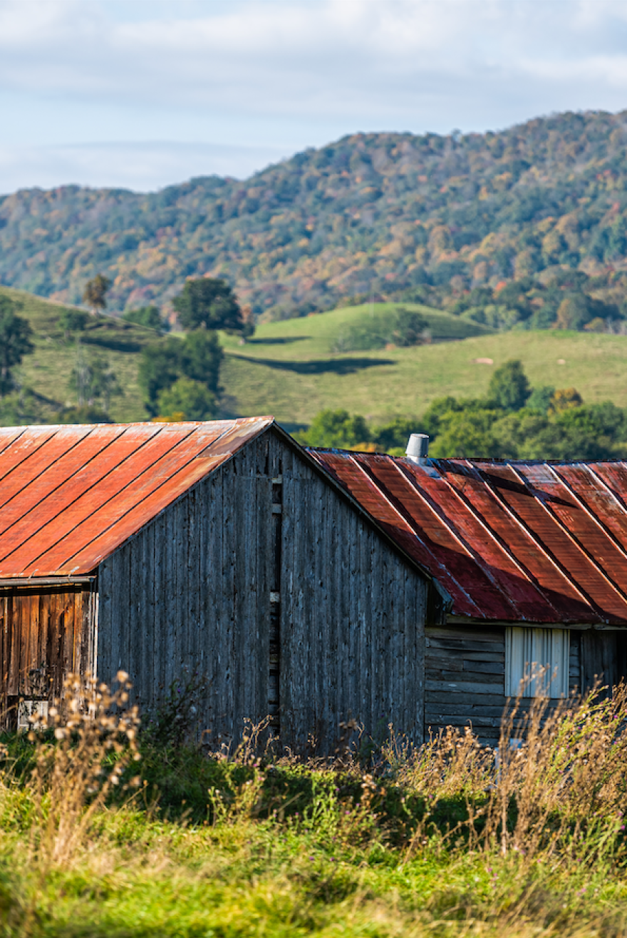 A barn at the foot of grass hills.