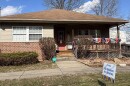 A small house is decorated with rainbow flags. A sign in front reads, "We Believe in Libraries."