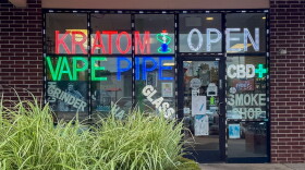 Storefront windows of a smoke shop advertising kratom in Oklahoma City.