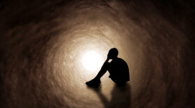 Teenage boy upset and covering his face in a dark tunnel.