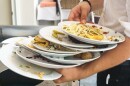A lot of dirty plates with scraps in the hands of a waiter at a restaurant.