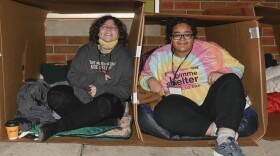 Two participants in the Phoenix Community Development Center's "Gimme Shelter" fundraiser try to get comfortable in their cardboard boxes. 