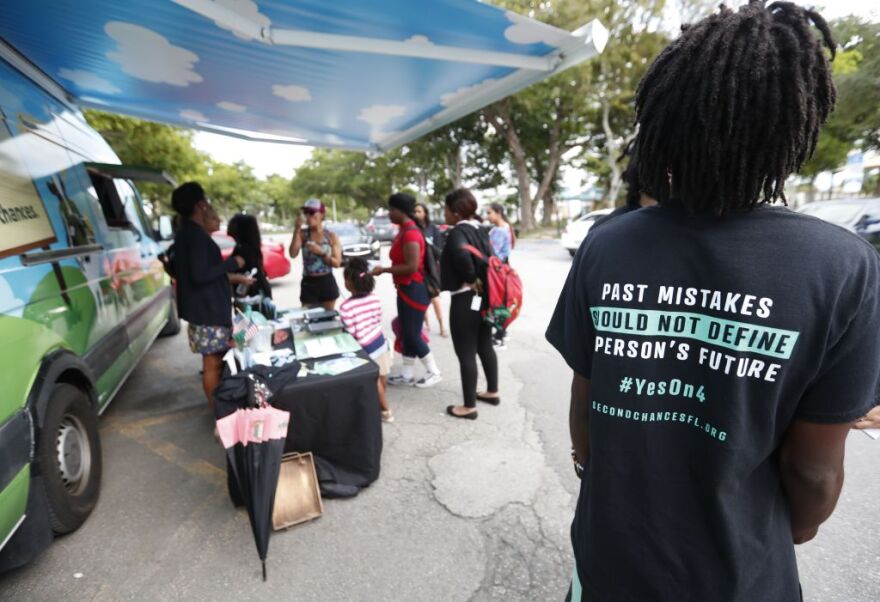 In this Monday, Oct. 22, 2018 photo, people gather around the Ben & Jerry's "Yes on 4" truck as they learn about Amendment 4 and eat free ice cream in Miami. Amendment 4 asked voters to restore the voting rights of people with past felonies in Florida.