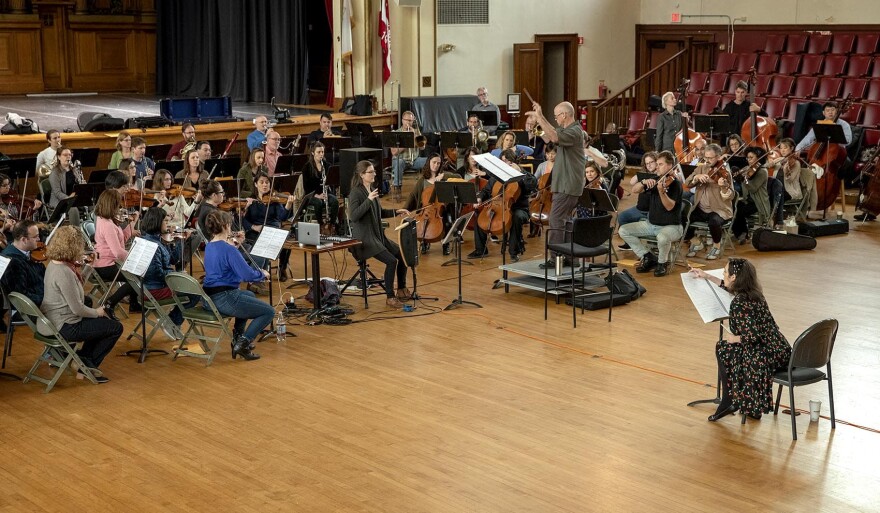 Thereminist Carolina Eyck, to the conductor's left, plays "Sirens: A Concerto for Theremin and Orchestra" with the Boston Modern Orchestra Project, as composer Dalit Warshaw watches, following the score. (Robin Lubbock/WBUR)