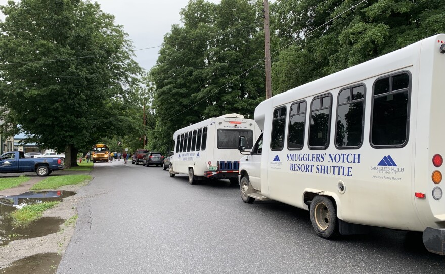 Two white shuttle buses are parked on a road