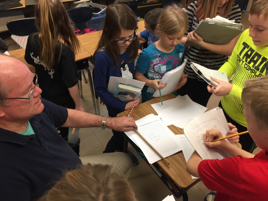 Students step back inside the classroom with their teacher Jim Jenkins to graph out the best locations in the soil to plant their seeds.