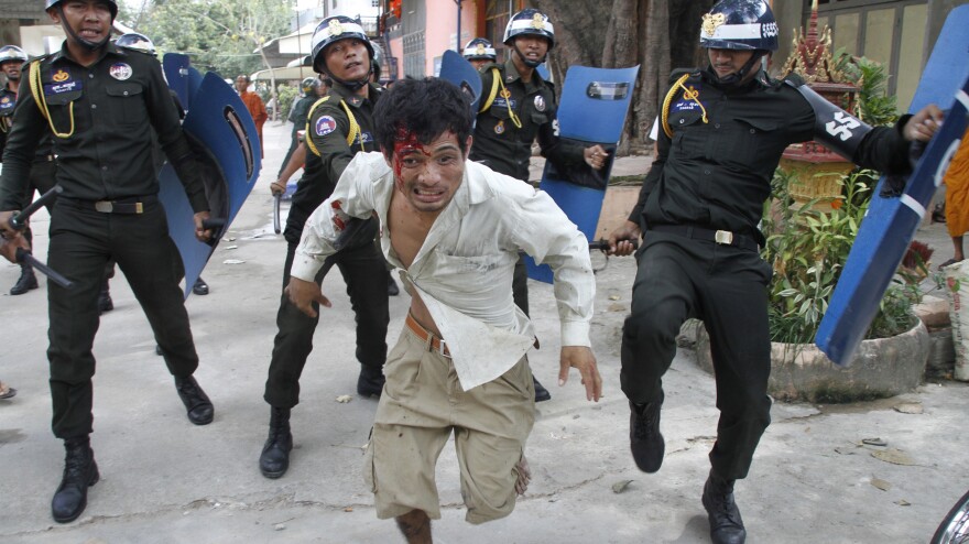 An injured Cambodian worker escapes from riot police in the compound of a Buddhist pagoda in Phnom Penh, Cambodia, on Tuesday. Police fired live ammunition at protesting garment workers outside the capital, injuring at least 20 people and killing a bystander.