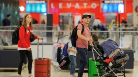 Two people carrying baggage walking through Tampa International Airport.