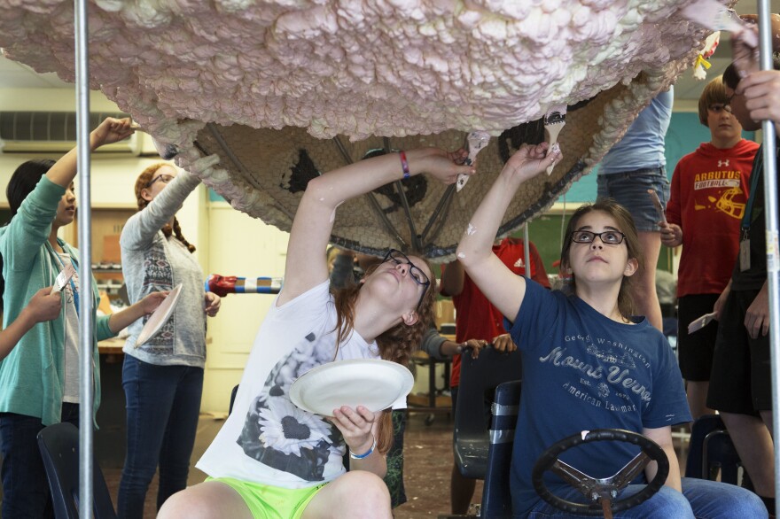 Abigail Morris (seated left) and Claire Doll paint the bottom of the brain sculpture as other students help with painting.