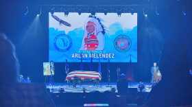 Photo of Arlan Melendez displayed on a digital screen in the GSR Grand Theater with his caskate below it.