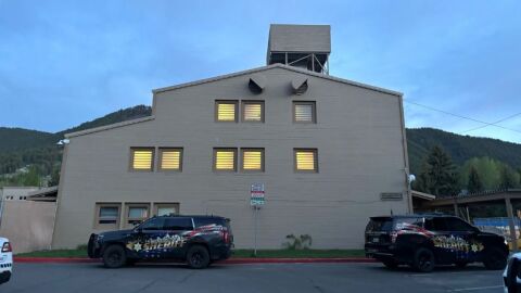 A tan building with two sheriff's vehicles outside of it.