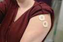 KBIA's Rebecca Smith arm - after receiving both her COVID-19 booster and flu shot in 2021 - there are two circular bandaids on her upper arm. 