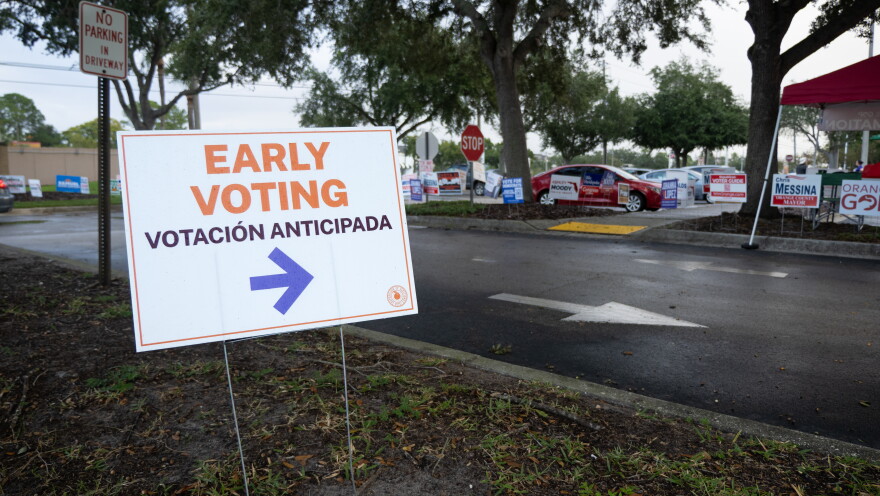 A sign directs early voters to election officials at the Orange County Public Library Alafaya branch on the morning of Monday, the first day of early voting in Orange County.