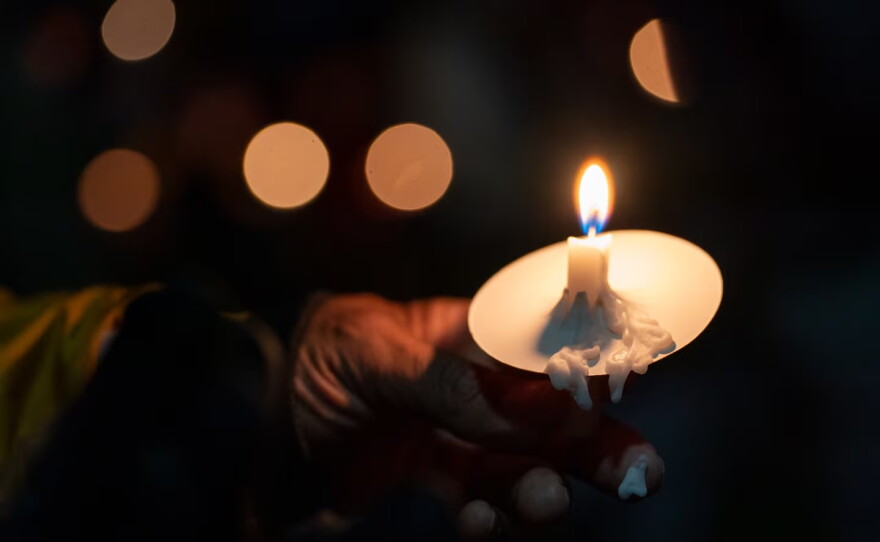 Candle wax melts onto an attendee’s finger during a vigil at Drake Park after three children and a teacher were killed in a mass shooting at Silver Rail Elementary School in Bend, Ore. on Oct. 15, 2026. The suspected shooter was a 16-year-old who entered the school and was killed by an armed bystander, bringing the total number of deaths to five.