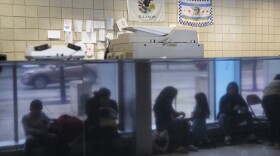 Immigrants from Venezuela are reflected in a marble wall while taking shelter at the Chicago Police Department's 16th District station on Monday, May 1, 2023. 
