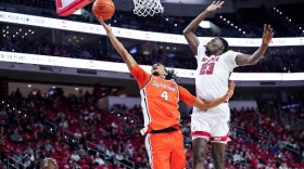 Syracuse forward Chris Bell (4, orange) finishes a layup in front of NC State forward Mohamaed Diarra in SU’s win over NC State on Feb. 20. (cuse.com)