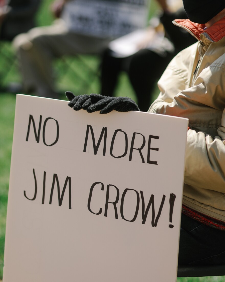 An attendee holds a sign that reads "No more Jim Crow!" during a voter rights rally at the Missouri State Capitol.