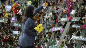 Holly Harmon places a rose into a memorial for victims of Hurricane Ian in Fort Myers, Fla., on Monday, Oct. 10, 2022. More than 100 died during the hurricane, with the greatest number in Lee County. 