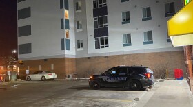 Black police SUV parked in a parking lot in front of a store and next to a large apartment building