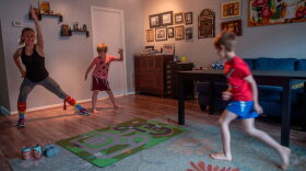 Mimicked by her son Daniel (C), Paulina Mansz, a group fitness instructor, records a workout session for her clients while her other son Javier plays, as she continues to instruct from home in Arlington, Virginia.