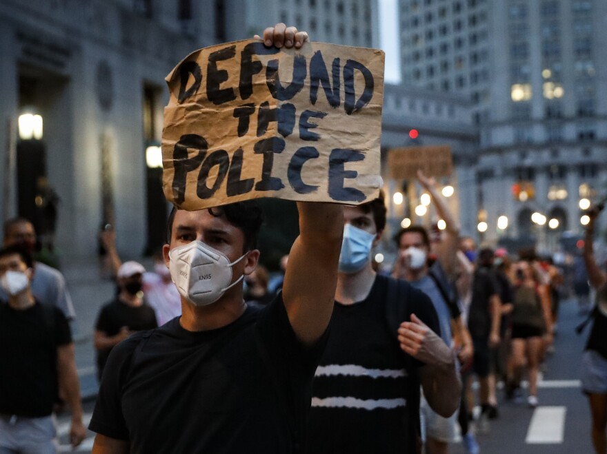 This photo from Thursday July 30, 2020, shows a demonstrator holding a sign that reads "Defund the police" during a protest march in New York.