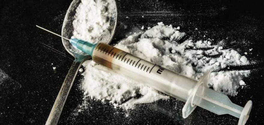 white powder on a black table and in a spoon with a syringe