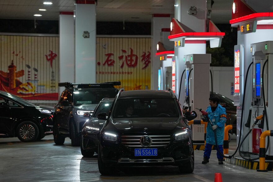 A gas station employee pumps fuel as other motorists wait in Beijing, Sunday, March 22, 2026. (AP Photo/Andy Wong)