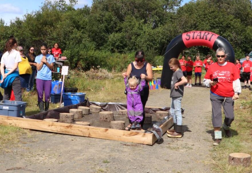  A young child is helped through the muddy logs.